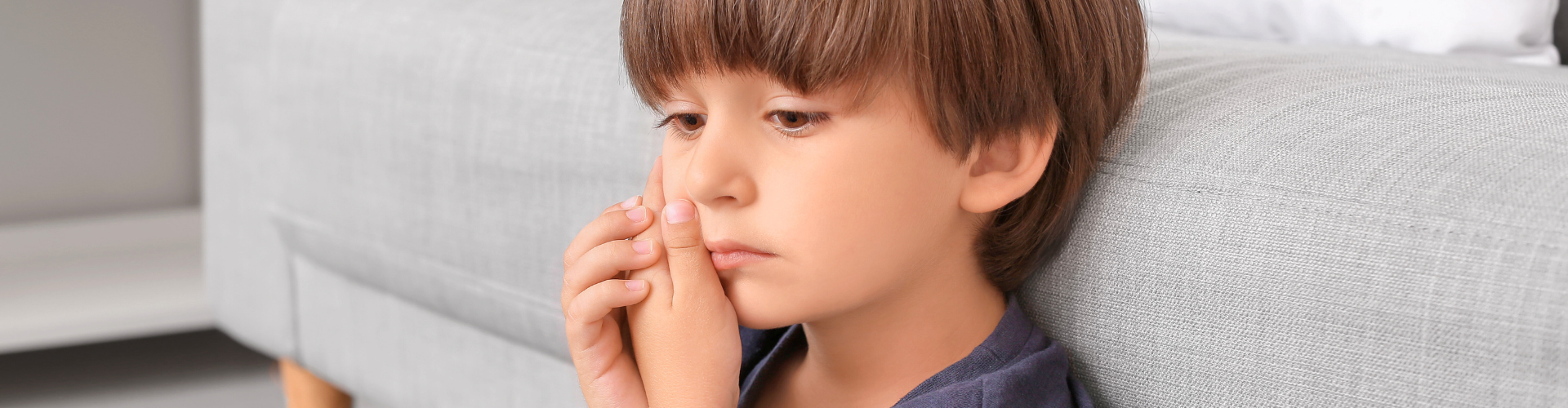 Boy holding his cheek in pain.